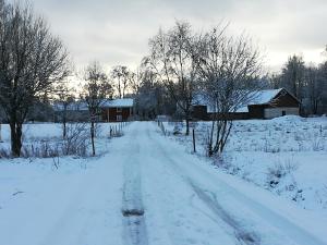 una carretera cubierta de nieve en un campo con un granero en Vekhyttegården, en Fjugesta