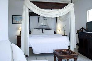 a bedroom with a white bed with a canopy at Zephyros in Paraga