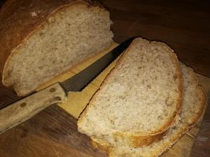 una hogaza de pan en una tabla de cortar con un cuchillo en Vekhyttegården, en Fjugesta