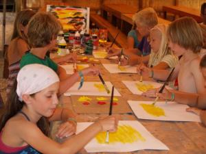 Un grupo de niños sentados alrededor de una mesa pintando en Amfibietreks, en Siniscola