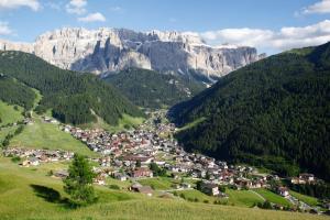 a village in a valley with mountains in the background at Hotel Garni Concordia - Dolomites Home in Selva di Val Gardena