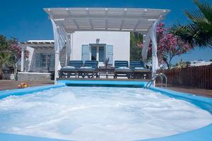 a large swimming pool with a pergola and chairs at Zephyros in Paraga