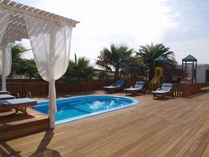 a swimming pool with chairs and an umbrella on a deck at Zephyros in Paraga