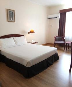 a hotel room with a large bed and a chair at Hotel Seri Malaysia Kuantan in Kuantan