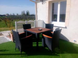 Une table et des chaises en bois sont disponibles sur la terrasse. dans l'établissement Le Soleil en Gironde, à Vrillant