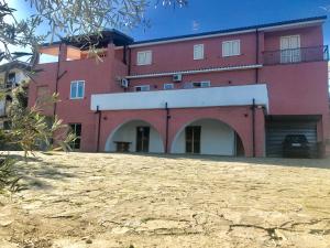 een rood gebouw met bogen en een stenen tuin bij Cilento in San Mauro Cilento