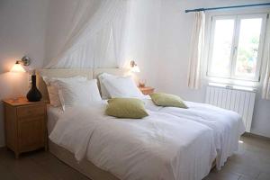 a bedroom with a large white bed with two pillows at Zephyros in Paraga