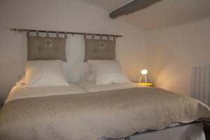 una camera da letto con un grande letto con cuscini bianchi di La maison de jules a Moustiers-Sainte-Marie