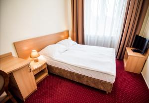 a bedroom with a bed and a desk and a television at Hotel Piast in Słupsk