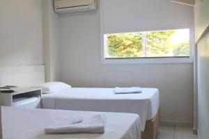 a white room with two beds and a window at MFG Hotel in Cianorte