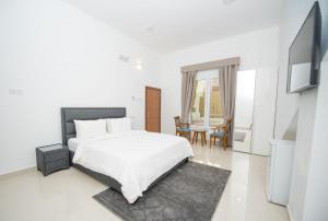 a white bedroom with a bed and a tv at Bedyiah Green Homes in Al Qābil