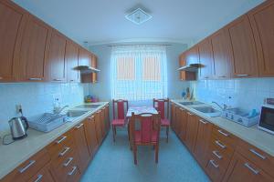 a kitchen with wooden cabinets and a table and chairs at Willa Kwiatano - Plac zabaw & Jacuzzi & Basen & Sauna - Budynek C in Grzybowo