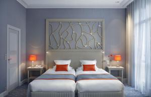 a bedroom with two beds and two tables with lamps at Splendid Etoile in Paris