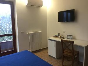 Ein Schlafzimmer mit Bett und Schreibtisch, an dessen Wand ein Fernseher hängt. in der Unterkunft Bed and Lemons in Piano di Sorrento