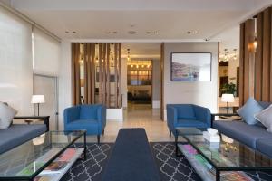 uma sala de estar com sofás azuis e uma mesa de vidro em The Conroy Boutique Hotel em Amã