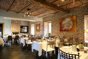 un restaurant avec des tables et des chaises et un mur en briques dans l'établissement Aparthotel Le Manoir du Capitaine, à Feluy