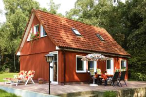 a red house with chairs and an umbrella on a deck at Ferienhaus Troge in Zinnowitz