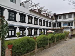 un grande edificio bianco con finestre e cespugli neri di Hotel Heranya a Kathmandu
