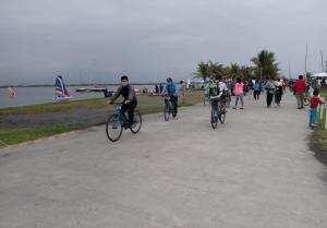 um grupo de pessoas a andar de bicicleta na praia em Da Peng Bay Homestay em Linbian