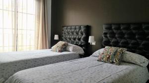 a bedroom with two beds and a large window at Hospederia V Centenario in Estepona