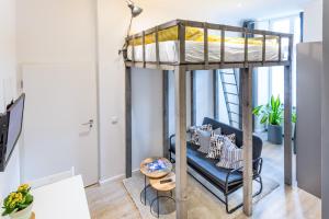 a loft bed with a couch and a chair in a room at Meedo I in Berlin