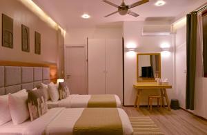 a bedroom with two beds and a table and a ceiling fan at Veli Vilaa in Dhiffushi