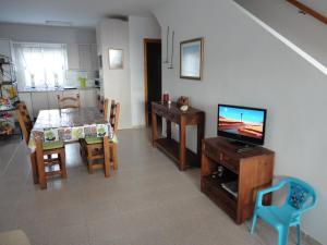 uma sala de estar com televisão e uma mesa com cadeiras em Comodidad en AGUAMARGA! em Agua Amarga