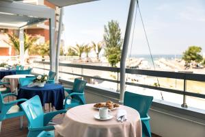 ein Restaurant mit Tischen und Stühlen und Blick auf den Strand in der Unterkunft Waldorf Palace Hotel in Cattolica