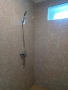 La salle de bains est pourvue d'une douche avec un pommeau de douche. dans l'établissement Murdhasari, à Ubud