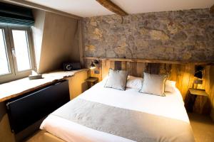 a bedroom with a bed and a stone wall at Hotel Victoria - Maison Caerdinael in Durbuy