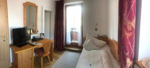 エルマウにあるLandhaus Kaiserblickのベッド、デスク、テレビが備わるホテルルームです。