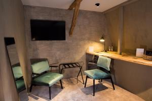 een kamer met drie stoelen en een tv aan de muur bij Hotel Victoria - Maison Caerdinael in Durbuy