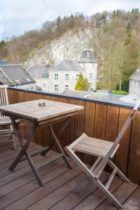 a wooden table and a chair on a deck at Hotel Victoria - Maison Caerdinael in Durbuy
