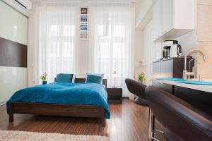 a bedroom with a blue bed and a kitchen at Viktoria Central Apartment in Budapest