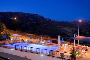 a swimming pool with chairs and umbrellas at night at Peyia Pearl in Peyia