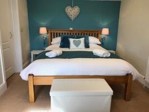 a bedroom with a large bed with blue walls at Crannaford Cottage in Broad Clyst