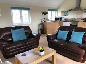 Sala de estar con 2 sofás de cuero y mesa de centro en Crannaford Cottage, en Broad Clyst