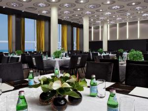 a dining room with tables and chairs and bottles at Dan Tel Aviv Hotel in Tel Aviv