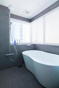 札幌的住宿－Private house Kuranoya Sapporo，浴室配有白色浴缸和淋浴。