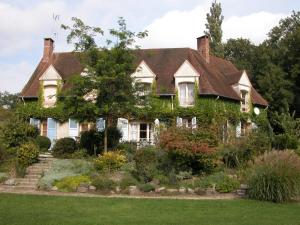 a house covered in ivy with a garden at Gîtes du Jardin Francais in Ermenonville