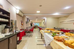 a restaurant with long tables filled with food at Rede Andrade Royal Criciúma in Criciúma