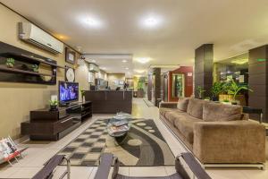 a living room with a couch and a tv at Tri Hotel Criciúma in Criciúma