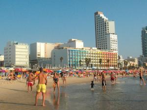 
a crowd of people walking on a beach near a large body of water at Dan Tel Aviv Hotel in Tel Aviv
