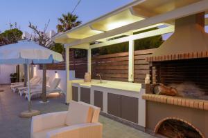 a patio with a kitchen and a fireplace at Spyros Apartments with Pool in Kalamaki