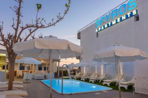 una piscina con sombrillas y sillas junto a un hotel en Spyros Apartments with Pool en Kalamaki