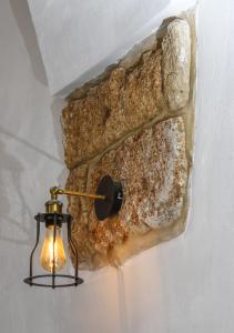 a light attached to a wall with a stone wall at Acre Two Wells Zimmer in Acre