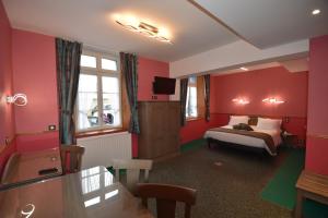 Schlafzimmer mit roten Wänden, einem Bett und einem TV in der Unterkunft Hôtel De Calais in Le Tréport