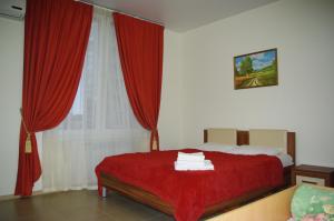 a bedroom with a bed with red curtains and a window at Guest House on Vinogradnaya in Sochi