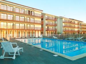 un hôtel avec une piscine en face d'un bâtiment dans l'établissement All Suites La Teste – Bassin d’Arcachon, à La Teste-de-Buch