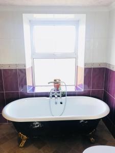 a bath tub in a bathroom with a window at Ned's Cottage in Kincasslagh